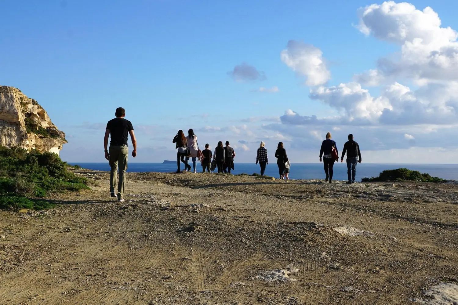Eine Gruppe von Menschen wandert oder spaziert entlang der Küstenklippen Maltas, möglicherweise in der Nähe der Dingli-Klippen oder eines anderen Aussichtspunkts mit Blick auf das Mittelmeer. von Persönlichkeitsentwicklung